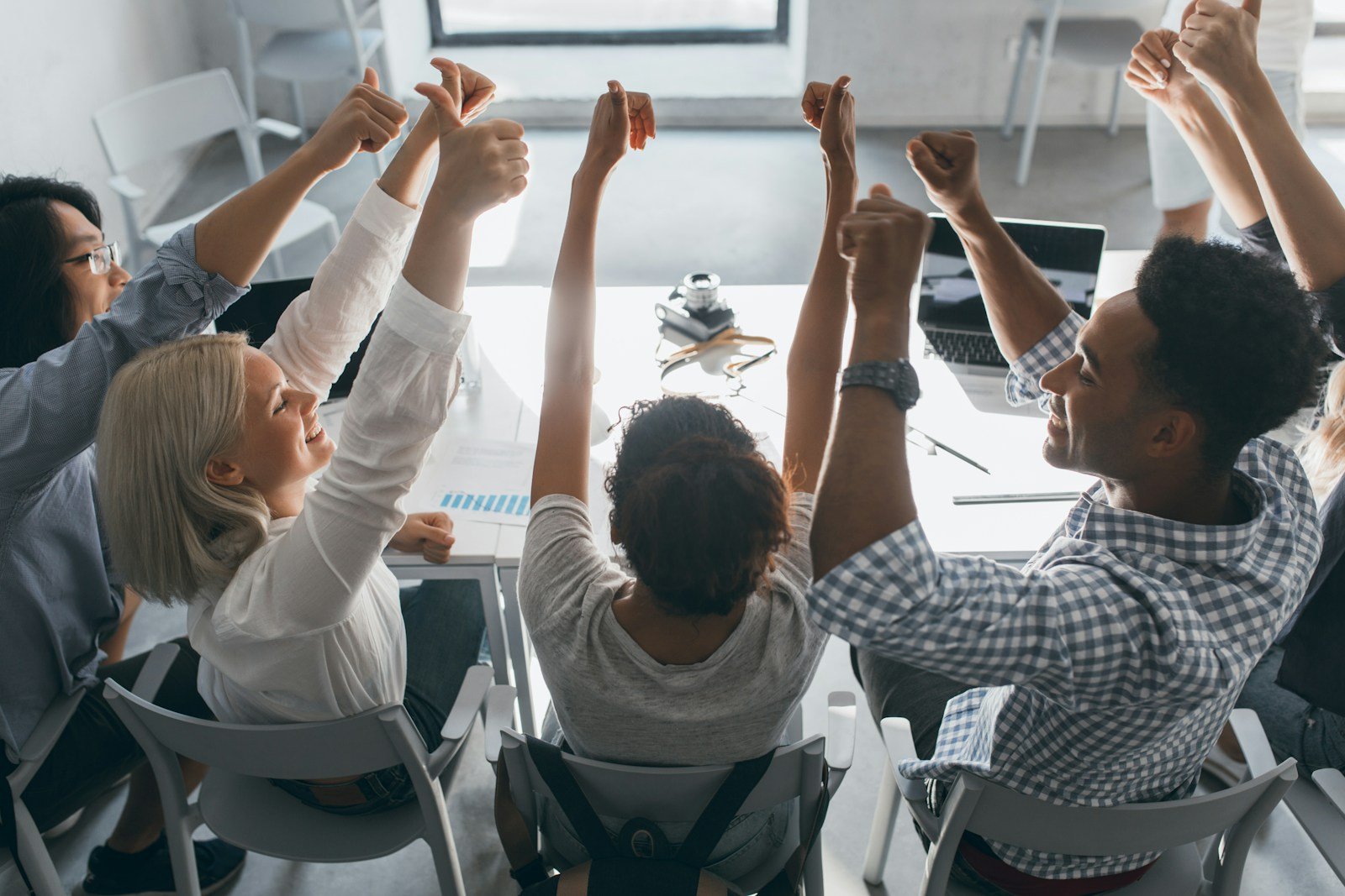 un groupe de personnes assises à une table levant la main pour approuver la croissance de l'entreprise